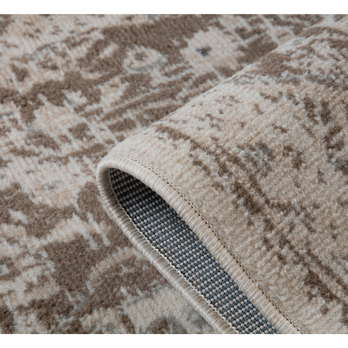 Rug edge close-up with curved corner, cream binding, and blue-gray underside backing.