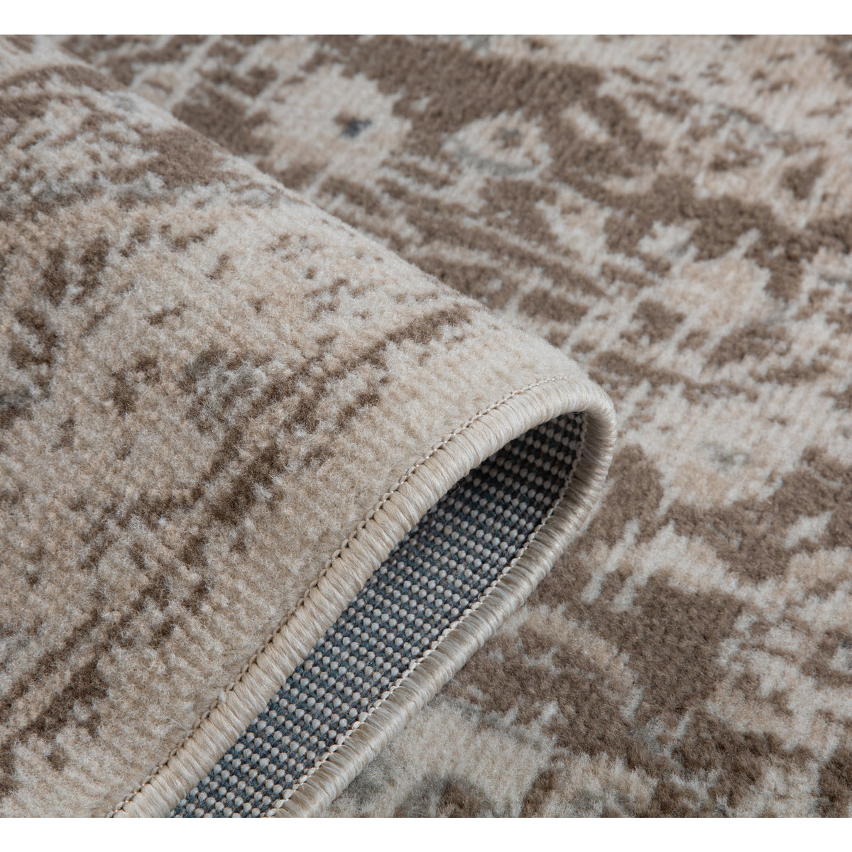 Corner close-up of rug with cream binding and blue-gray woven backing visible from edge.