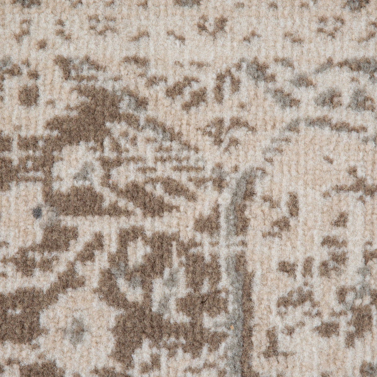 Close-up of light cream rug with taupe and brown abstract pattern and distressed look.