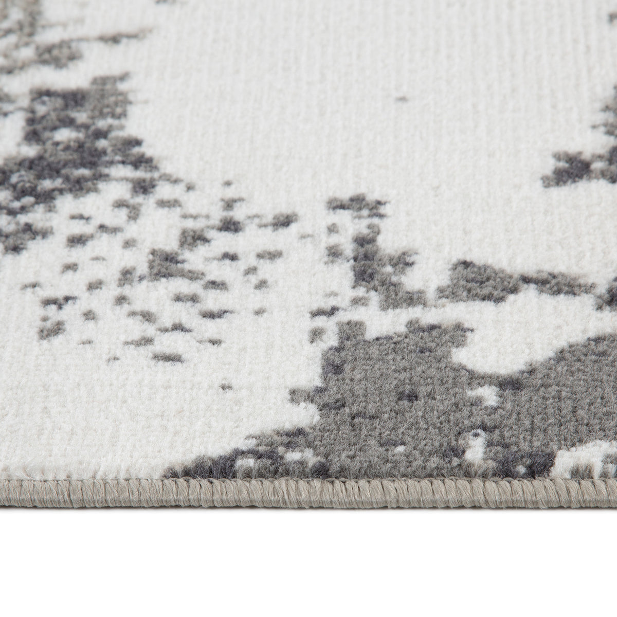 Ivory and dark gray area rug close-up with abstract pattern and textured low pile.