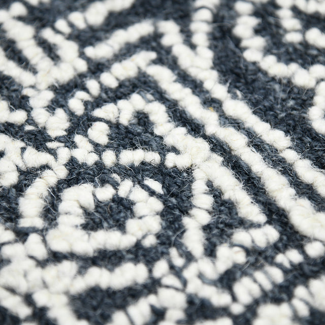 Rectangular area rug close-up of navy-charcoal and white geometric lines and motifs