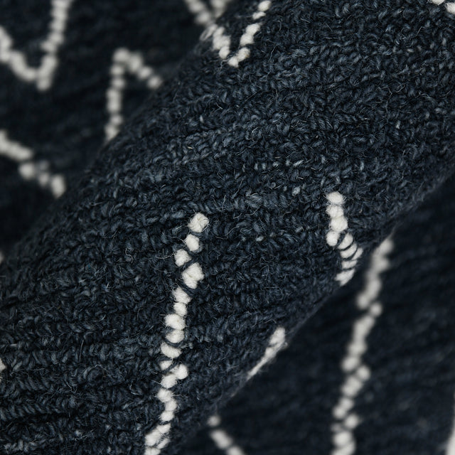 Rectangular area rug close-up showing dense looped pile and crisp white geometric accents