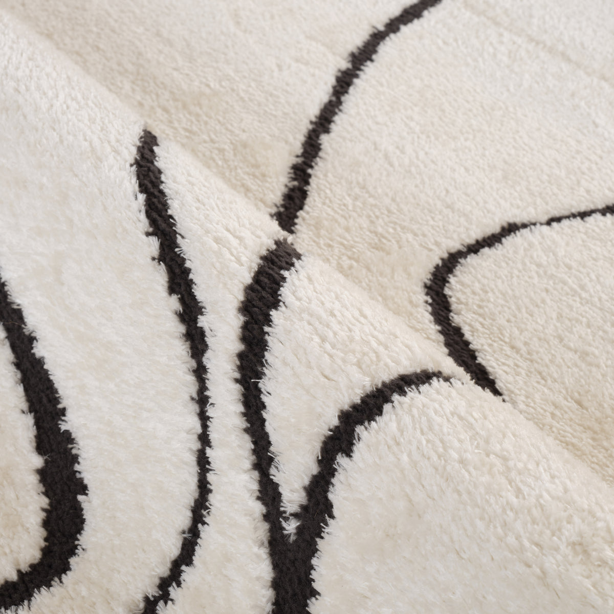 Close-up of ivory area rug pile with black outline shapes and textured weave