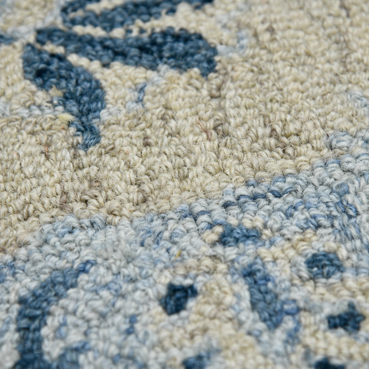 Close-up of light blue and cream floral hand-hooked rug texture with navy pattern