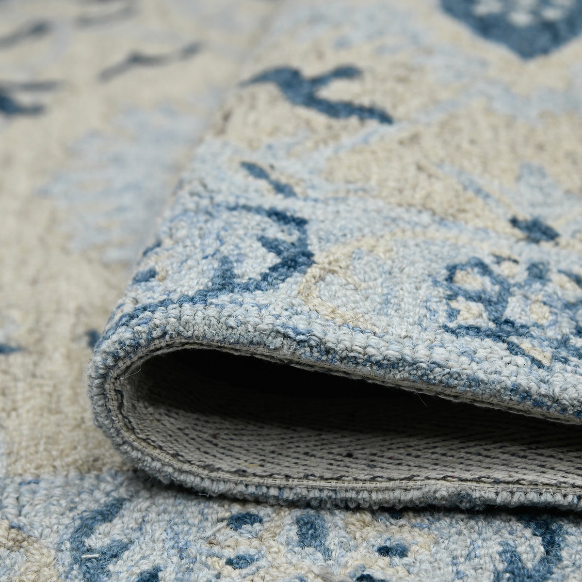 Light blue rug edge with woven underside and stitched border, navy-and-cream pattern
