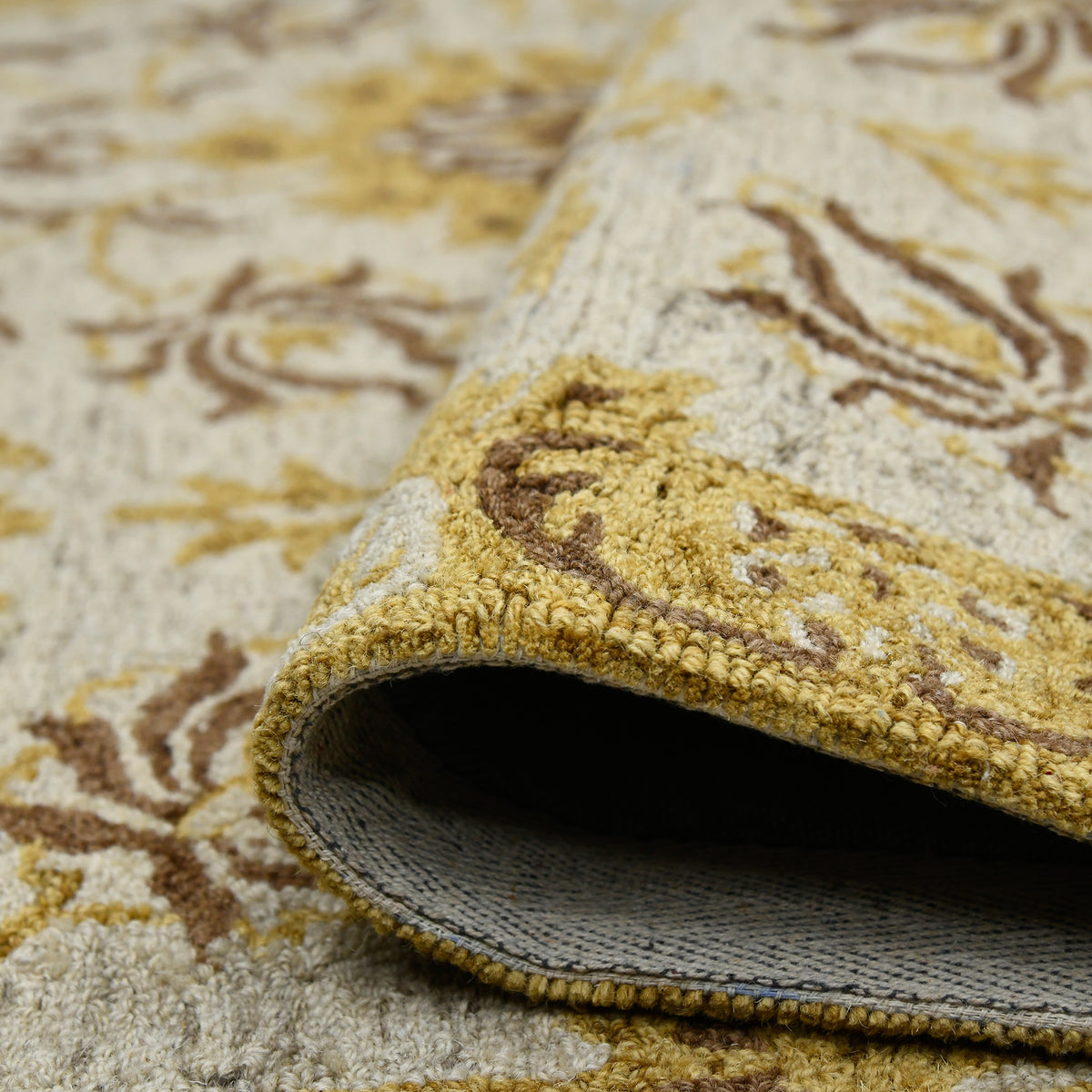 Floral area rug corner showing folded edge and dark backing panel