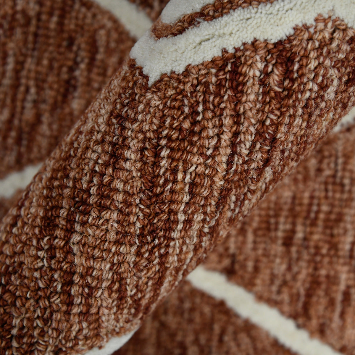 Hand-hooked rust geometric rug detail with thick braided texture and cream border