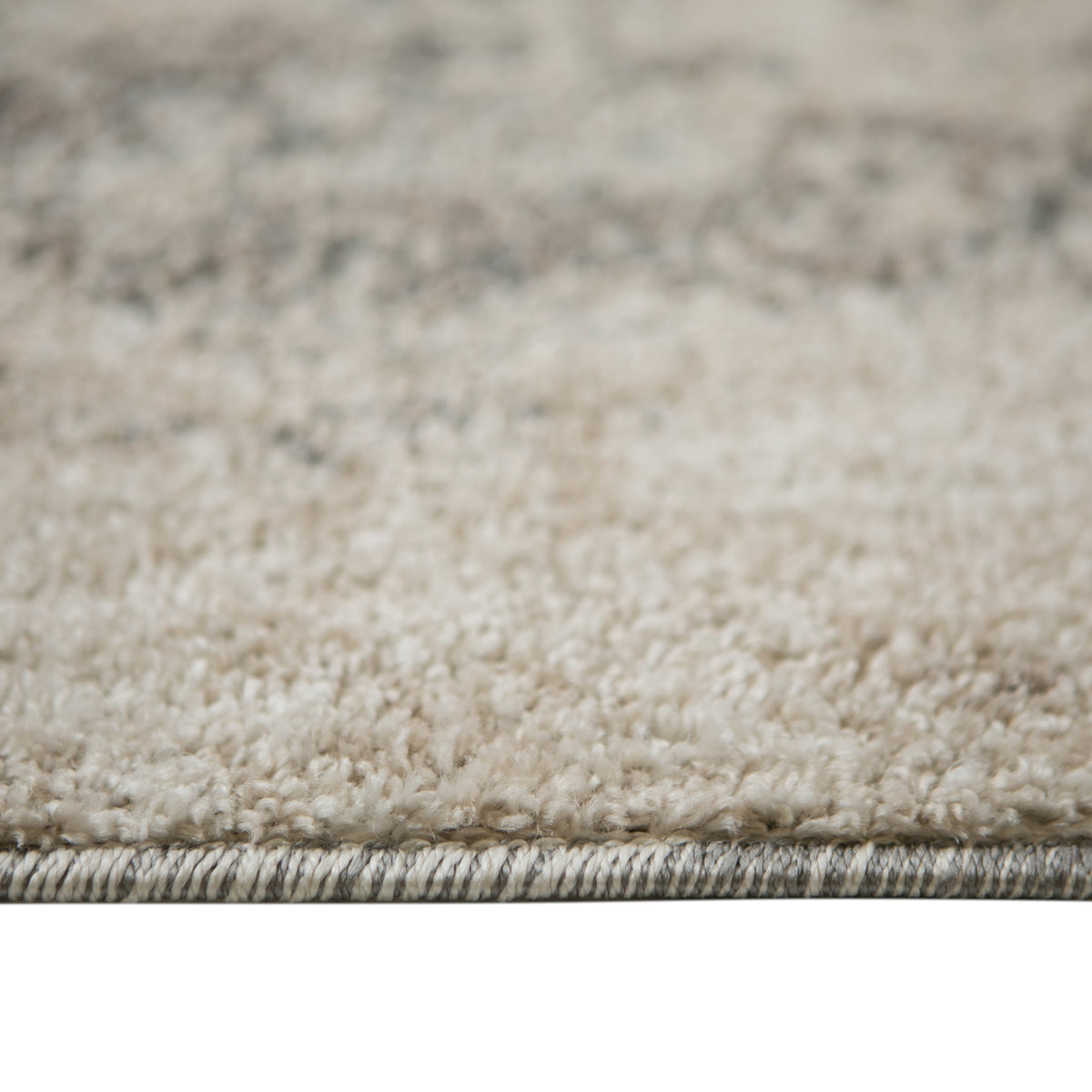 Close-up of rug border with layered edge stitching on beige and gray fibers.
