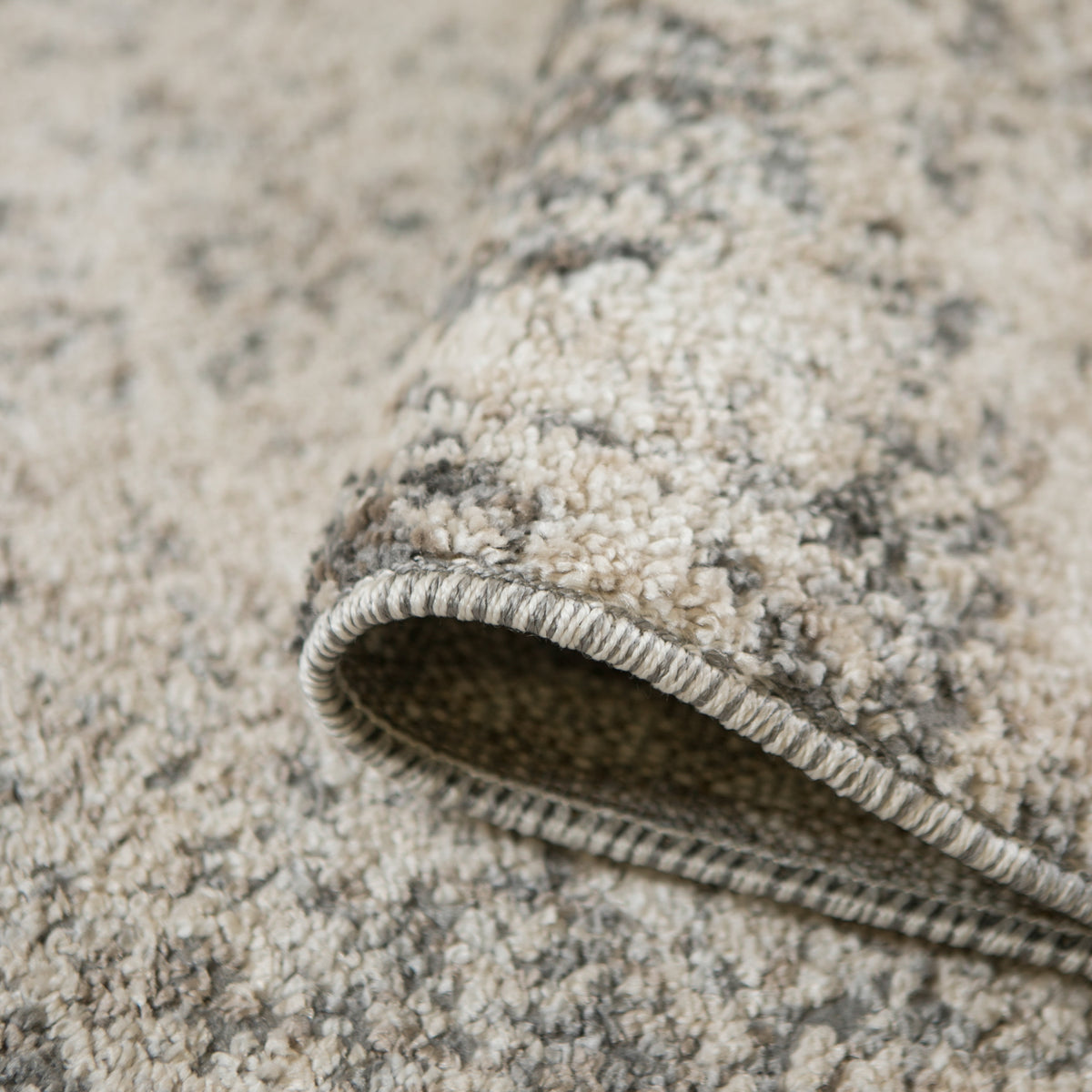 Close-up of rug corner edge with stitched border and dark backing underside.