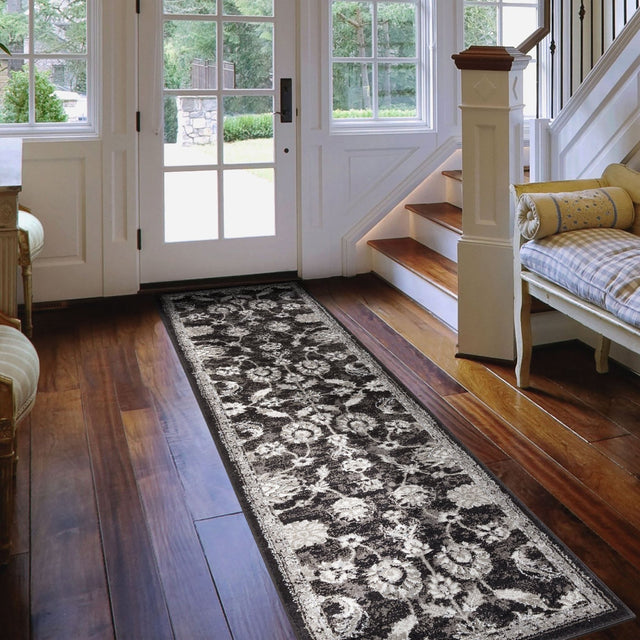 Long rectangular black and ivory area rug with distressed floral geometric pattern