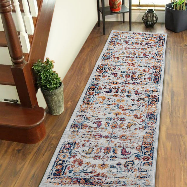 Rectangular ivory area rug with multicolor floral medallion and patterned border.