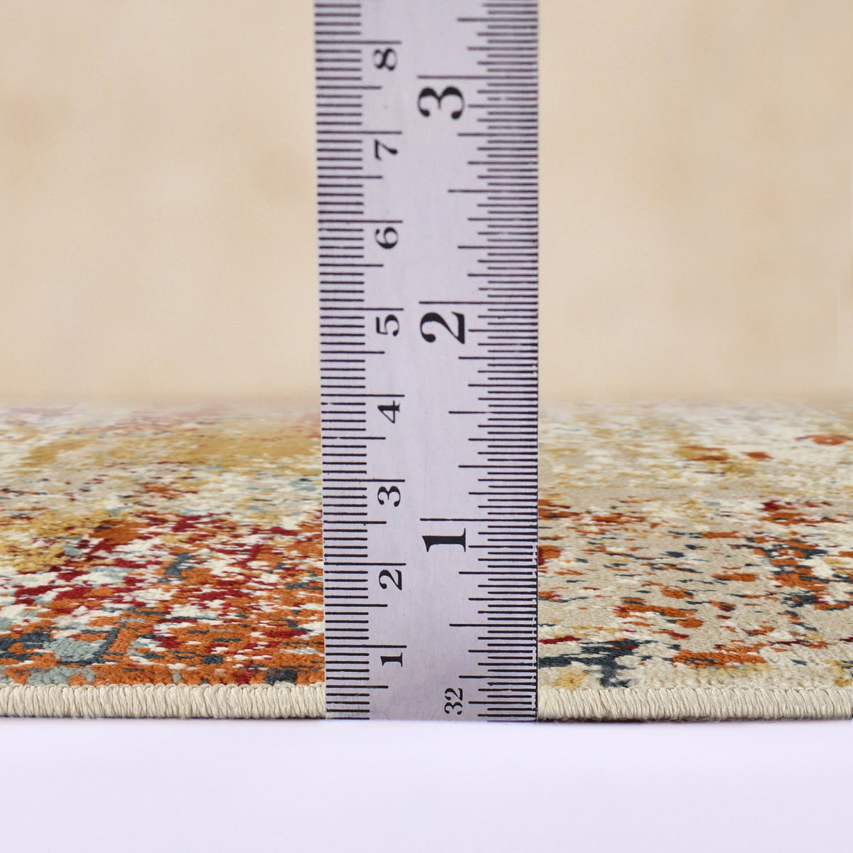 Area rug edge with measuring ruler across ivory and orange distressed pattern