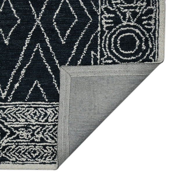 Rectangular area rug corner with charcoal-and-white geometric pattern and flat woven edge