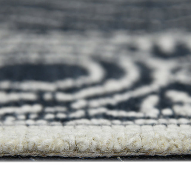 Rectangular area rug border close-up with charcoal/white geometric pattern and looped texture