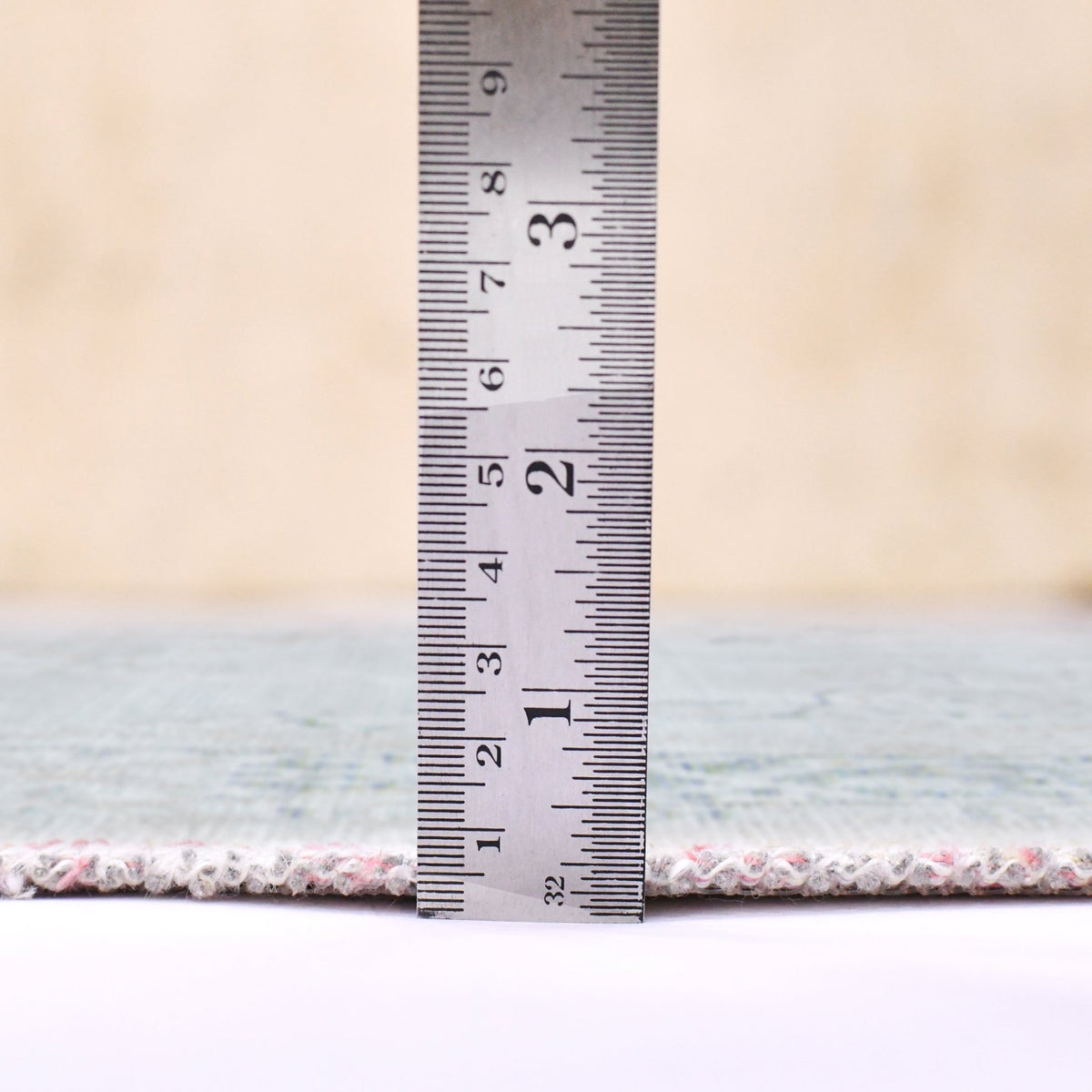 Sea mist area rug edge shown with measuring ruler at the rug border