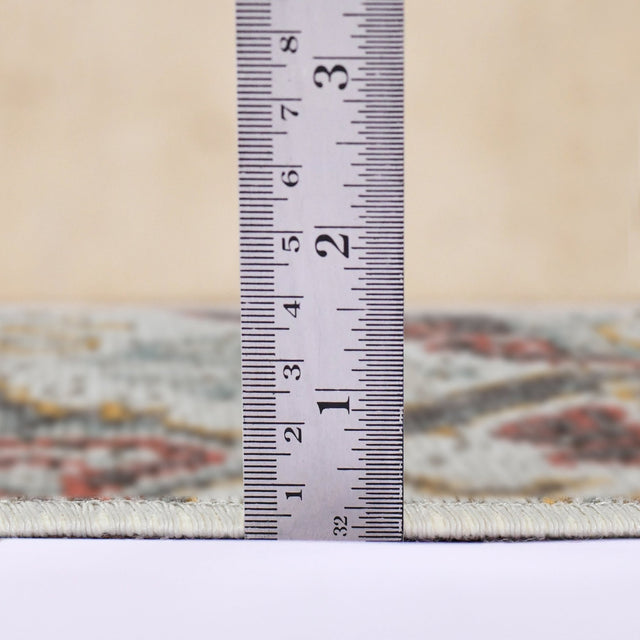 Beige area rug edge with pile detail, measured with a height ruler