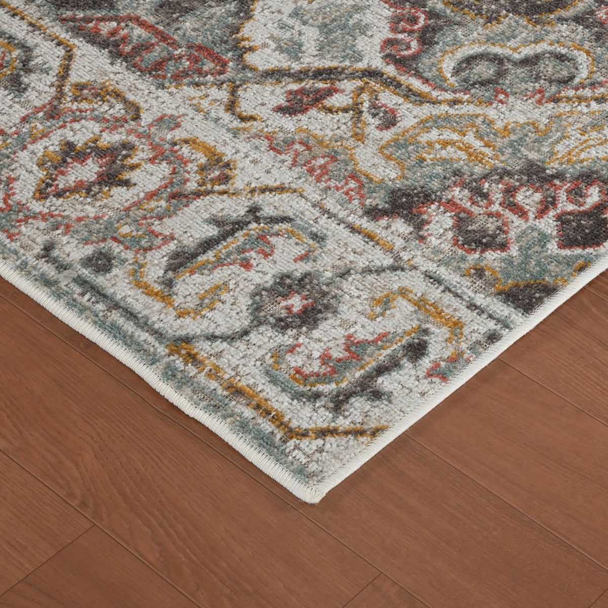Beige area rug corner with distressed geometric medallion pattern and short fringe