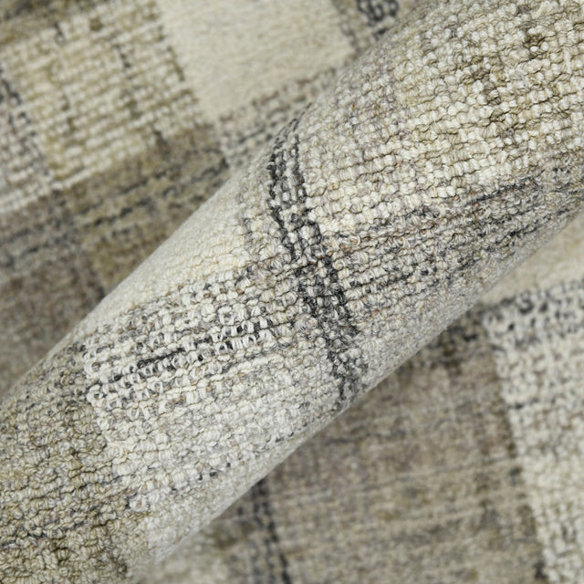 Close-up of plaid rug edge showing stitched binding and multitone fibers.