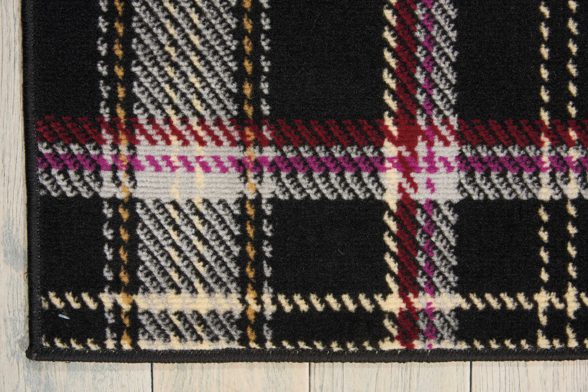 Close-up black plaid area rug with cream, red, purple, and gold grid texture