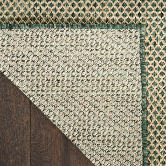 Green and beige rug corner with diamond lattice pattern and fringeless edge detail