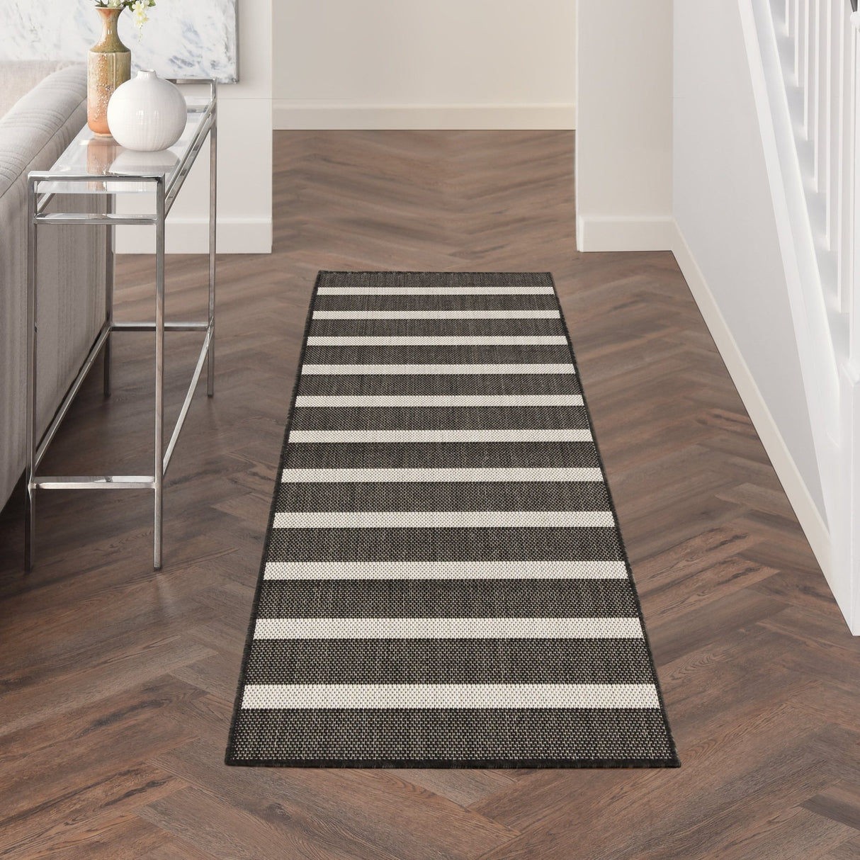 Rectangular black and ivory striped rug with stitched border and low pile