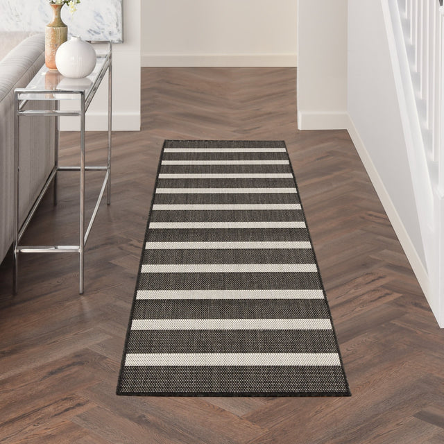 Rectangular black and ivory striped rug with stitched border and low pile