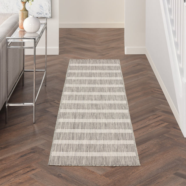 Rectangular grey-and-ivory striped rug laid in hallway on dark wood floor