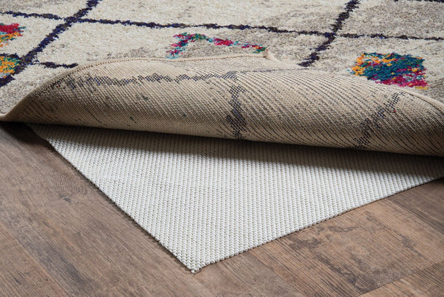 Beige cushioned rug pad with textured top and non-slip backing, layered under rug edge