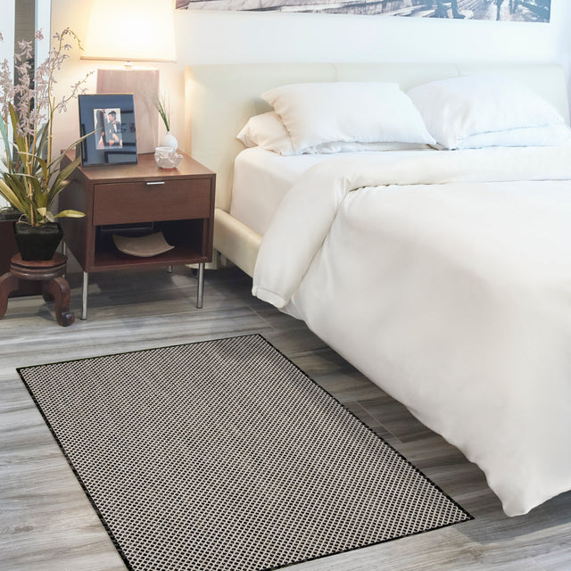 Black and white geometric area rug placed beside a bed in bedroom