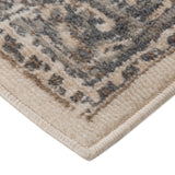 Light beige corner area rug with blue-gray geometric pattern and fringed trim.