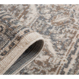 Light beige rug corner with blue-gray underside binding and geometric medallion pattern.