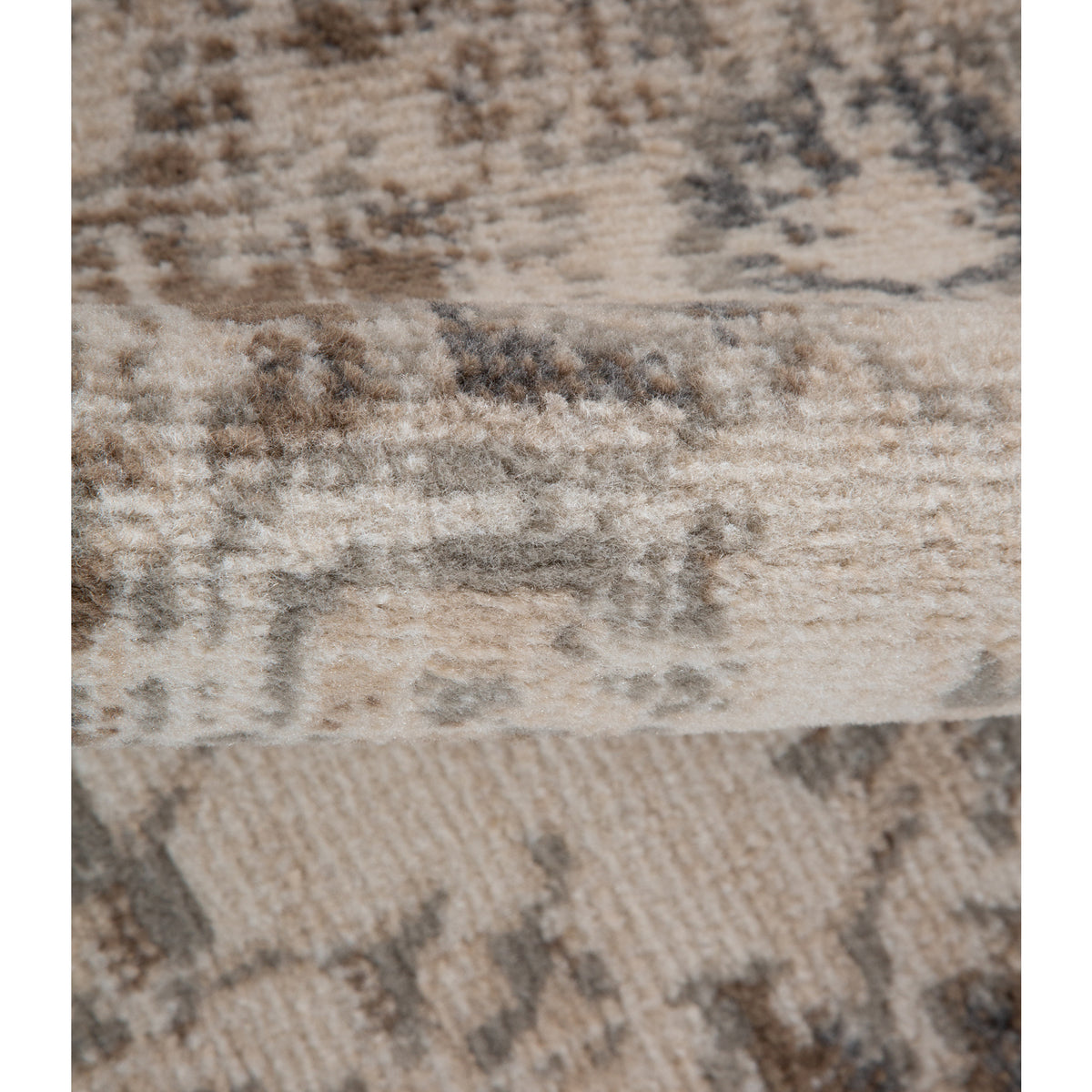 Light beige area rug surface with blue-gray geometric motifs and fringed edge detail.