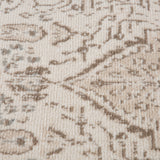 Close-up texture of light cream rug with taupe and brown abstract pattern lines.