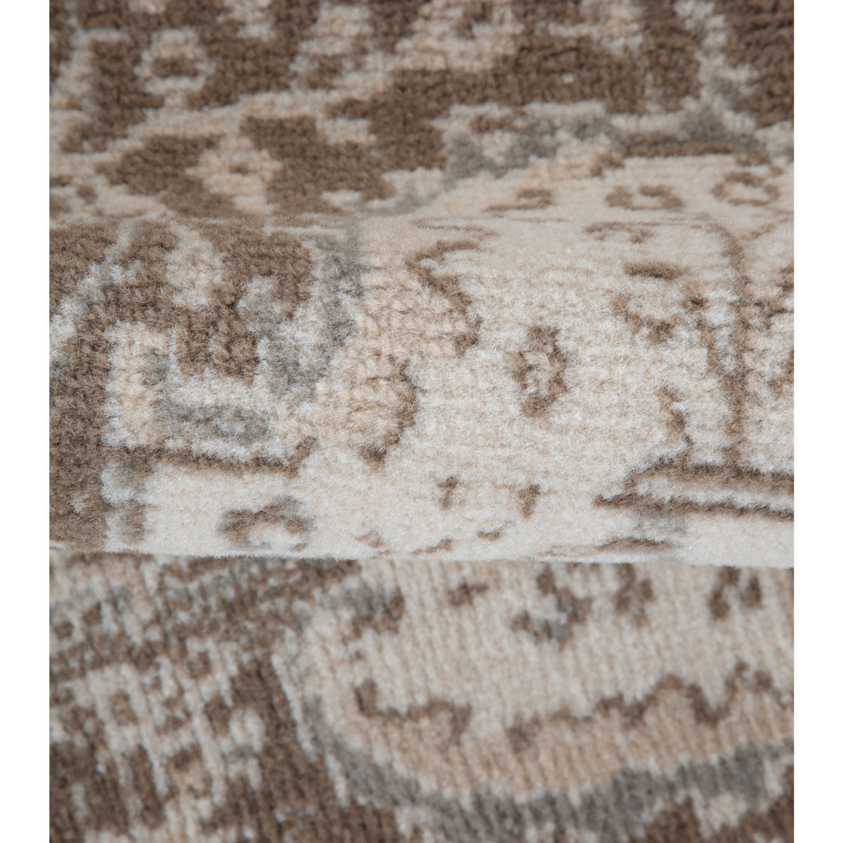 Close-up of light cream and brown traditional rug pattern with geometric motifs.