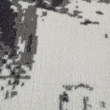 Ivory and dark gray area rug close-up with abstract blocks and scattered marks.