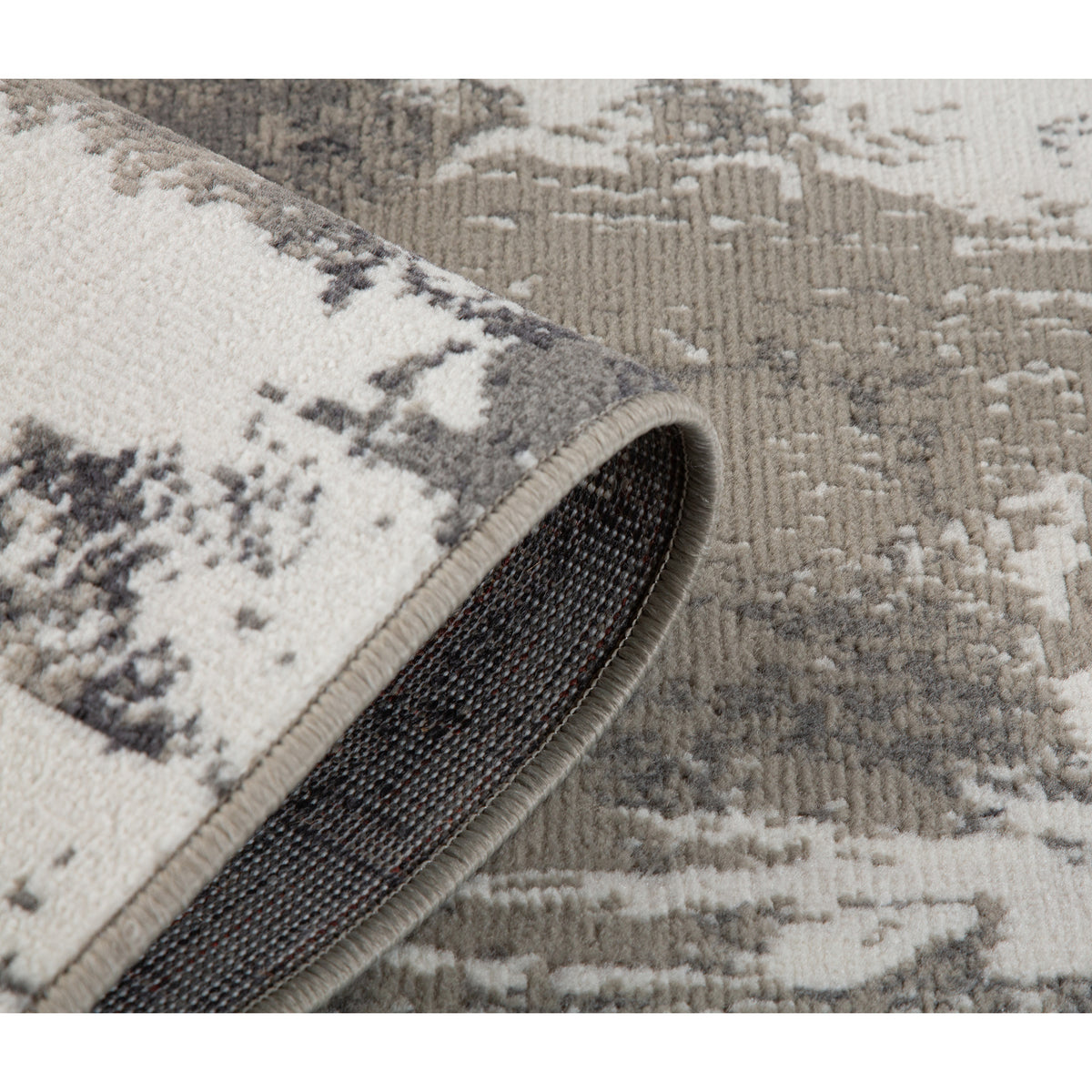 Corner view of ivory and dark gray area rug with textured backing and abstract motifs.