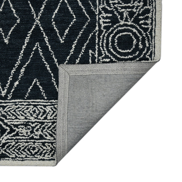 Rectangular area rug corner with charcoal-and-white geometric pattern and flat woven edge