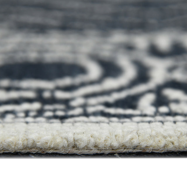Rectangular area rug border close-up with charcoal/white geometric pattern and looped texture