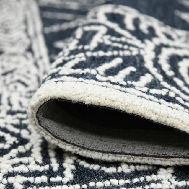 Rectangular area rug close-up showing charcoal/white pattern and low, looped pile
