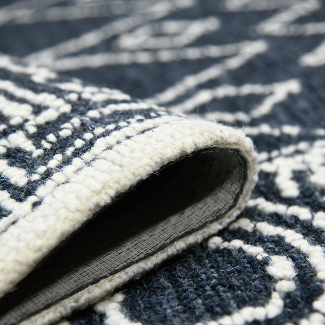 Rectangular area rug rolled edge close-up showing charcoal underside and white top pile