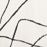 Ivory area rug close-up with connected black geometric curves and corners