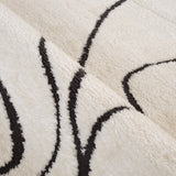 Close-up of ivory area rug pile with black outline shapes and textured weave