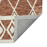 Geometric rust area rug with cream X and diamond shapes, folded edge detail