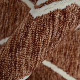 Hand-hooked rust geometric rug detail with thick braided texture and cream border