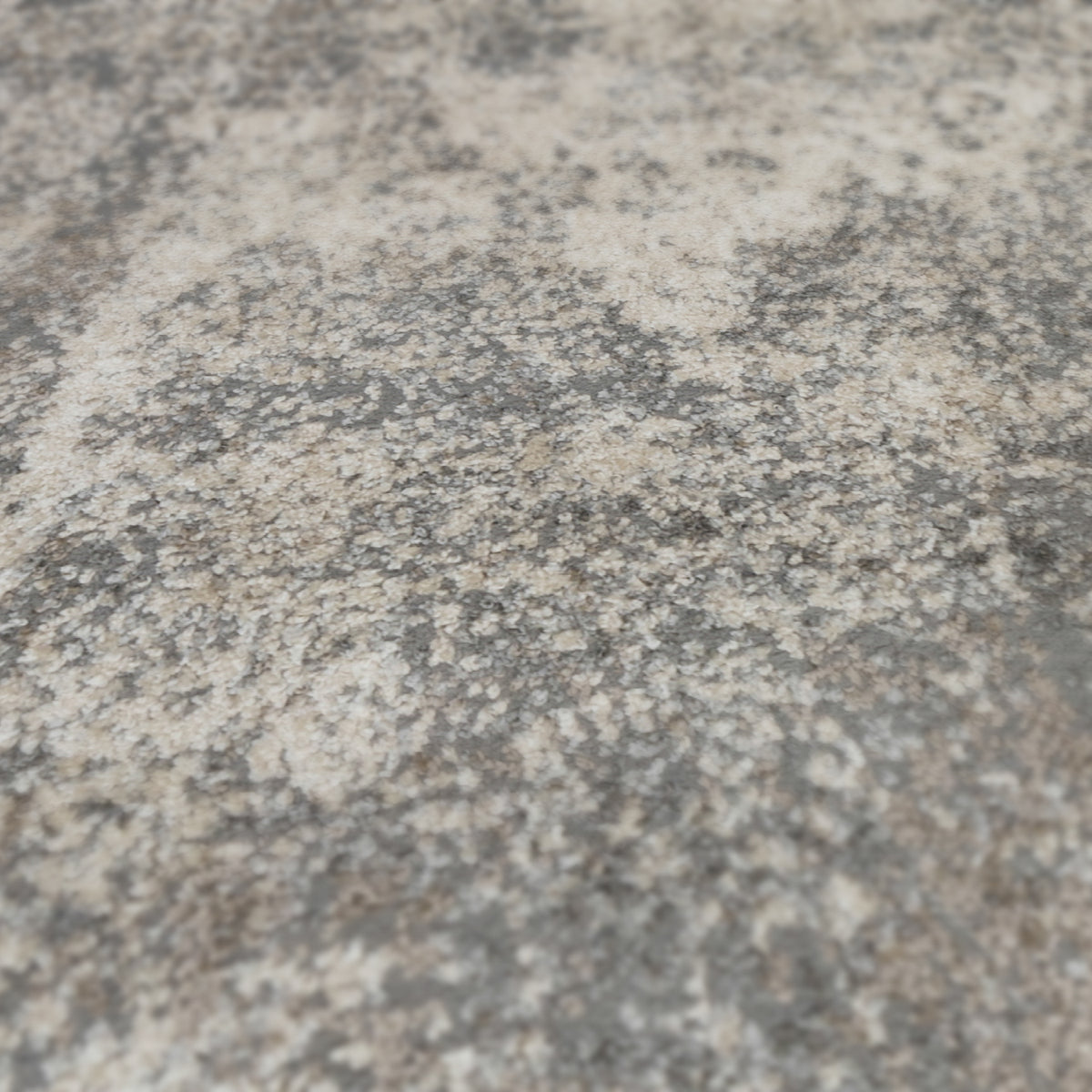 Surface view of light gray and beige distressed area rug with speckled pattern.