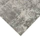 Corner of a light gray and beige area rug with abstract distressed look.