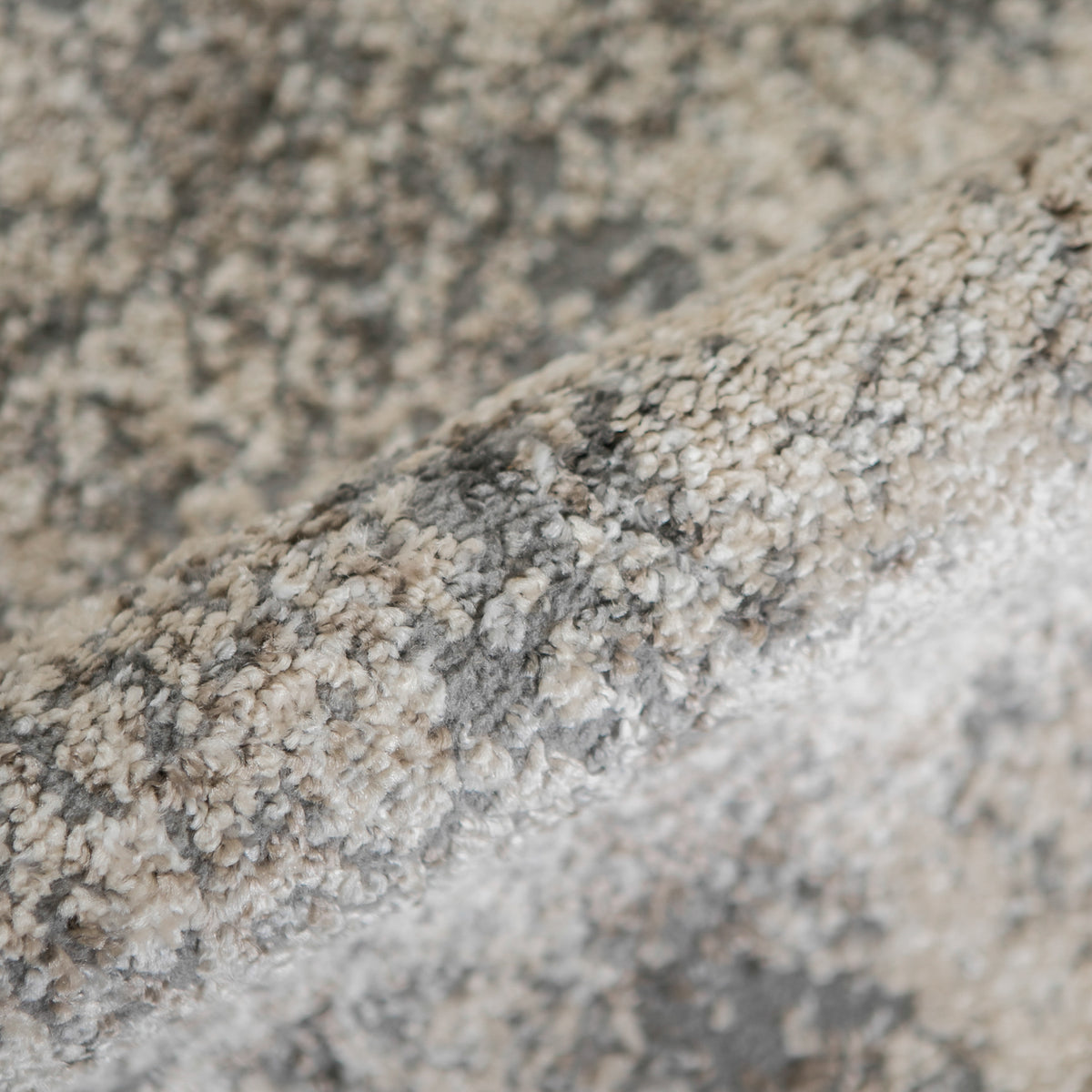 Close-up texture of gray and beige area rug with short, dense loop pile.