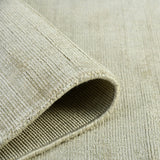 Sand area rug rolled edge with visible binding and looped weave texture.
