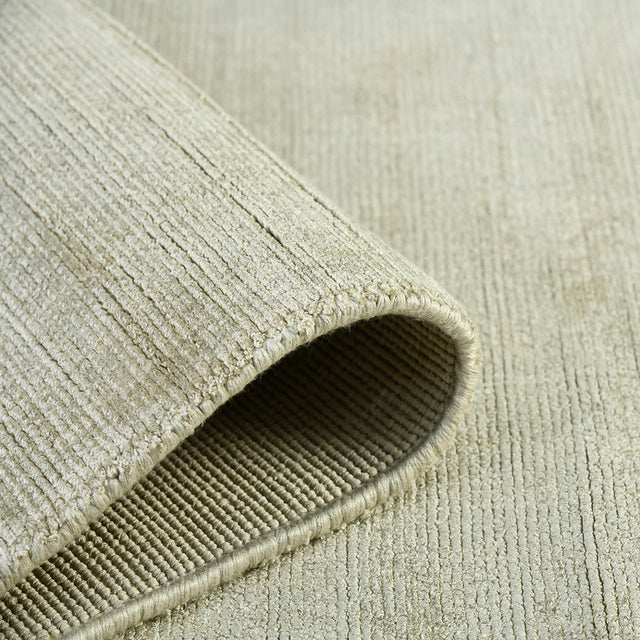 Sand area rug rolled edge with visible binding and looped weave texture.