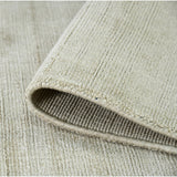 Rectangle area rug showing folded edge and dense striped weave in light sand tones.
